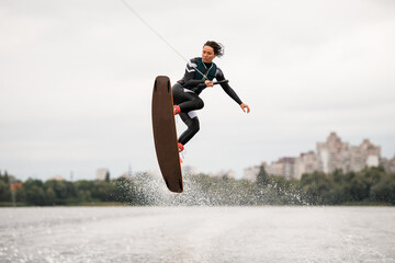 young energetic woman doing extreme jumps over the wave on a wakeboard
