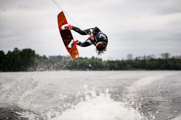 athletic woman doing flips and jumping over the water on wakeboarding board
