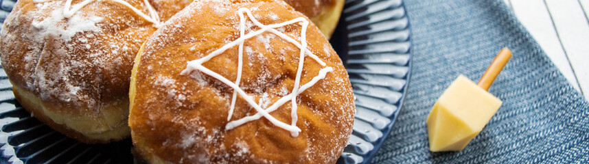 Happy Hanukkah banner. A traditional treat of doughnuts with David star and dreidel made from cheese and biscuit sticks. Copy space