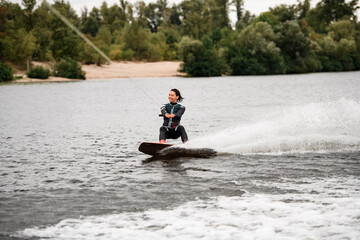 handsome woman wakeboarding on board on the river water on summer day