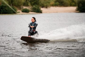 healthy sportive woman wakeboarding on board on the river water on summer day