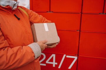 Post automat terminal and hand with parcel on the street. Parcel shipping service or delivery...