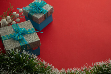 Christmas background with gift boxes with blue bow, green branches and red background