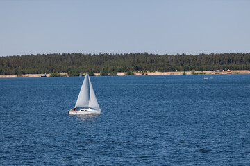 A boat with white sails floats on the river