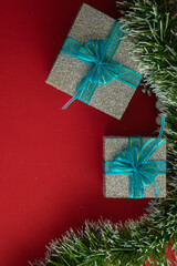 Vertical Christmas background with gift boxes with blue bow, green branches and red background