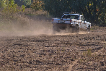 A unique passenger car is made in a single copy. A thick cloud of dust rises behind a pickup truck...