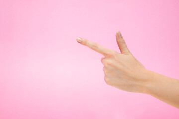 Woman's hand making shooting gun, gesture. hand pistol gesture on isolated pink background. Woman hand pointing with one fingers.