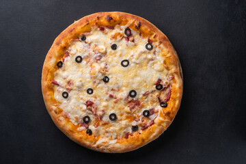 Home pizza with sausage, cheese, olive, pepper, Spices on black background. Supreme Hot Pizza