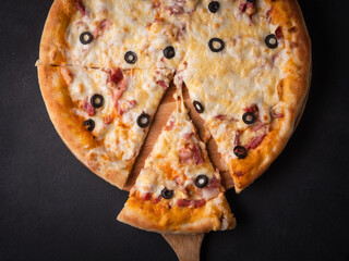 Home pizza with sausage, cheese, olive, pepper, Spices on black background. Supreme Hot Pizza