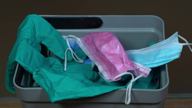 the doctor in the hospital throws used and dirty masks and plastic gloves in the trash can - waste caused by Covid-19 Coronavirus