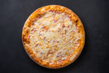 Round baked pizza with tomato, pepper, sausage, cheese on a black background. 