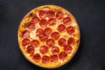 Pepperoni pizza with sausage on a dark background. - obrazy, fototapety, plakaty