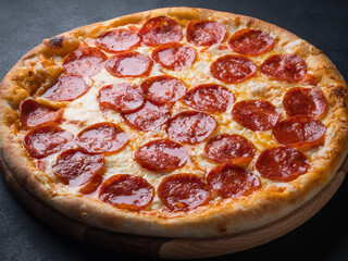 Pepperoni pizza with sausage on a dark background.