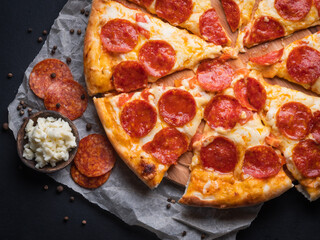 Pepperoni pizza with sausage on a dark background.