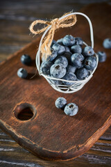 Tiny basket of blueberries on a wooden background