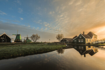 Obraz premium Traditional green dutch house with little wooden bridge against blue sky in the Zaanse Schans village.