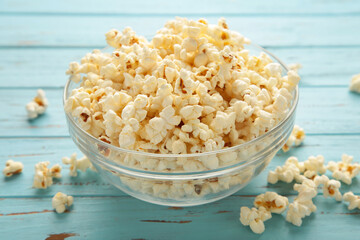 Fresh popcorn in bowl on blue table.