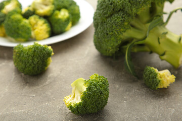 A bowl of cooked green broccoli on grey background.