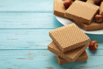 Square chocolate wafer biscuits with hazelnut on blue background.