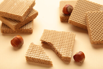 Square chocolate wafer biscuits with hazelnut on beige background.