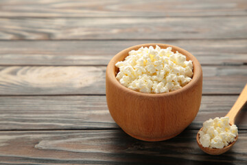 Cottage cheese for breakfast in wooden bowl on brown background.