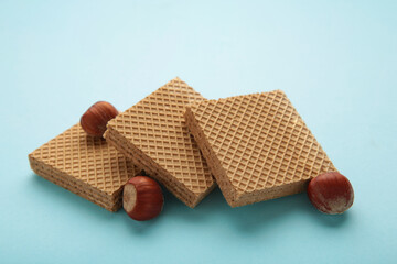 Square chocolate wafer biscuits with hazelnut on blue background.