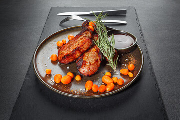 A grilled ribeye steak served , baby carrot, rosmarin and sauce