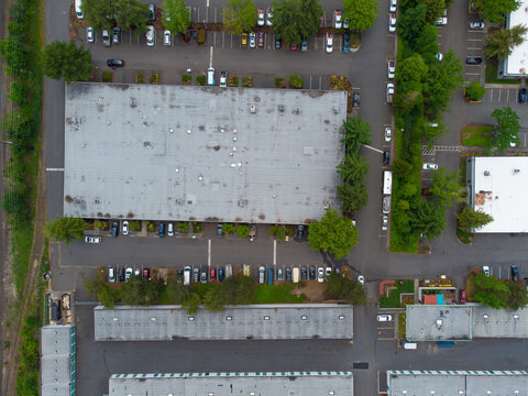 Aerial view. Paved area, car parking. Green trees, parked cars, roofs of large buildings. Abstraction. no people. Infrastructure, tourism, travel.