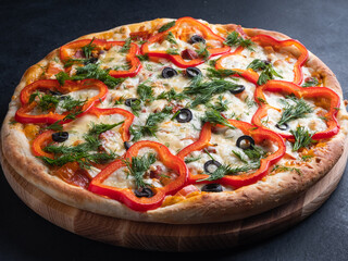 Homemade delicious pizza decorated with bell pepper rings, olives, dill.