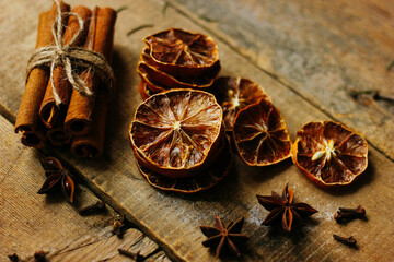 A bunch of cinnamon sticks, dried lemons, cloves and anise on a wooden table