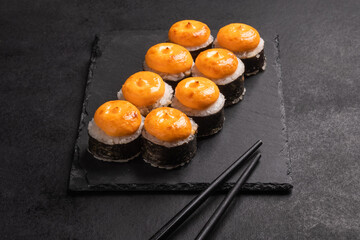 Baked rolls on the board with black  chopsticks. Delicious asian food.