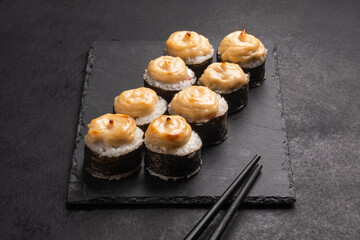 Baked rolls on the board with black  chopsticks. Delicious asian food.