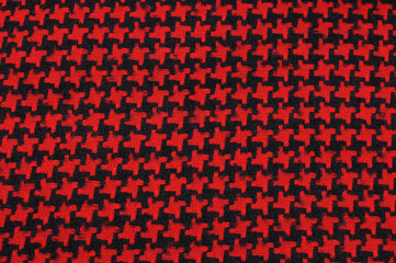 Black fabric with red repeating geometric patterns. Material for outerwear.