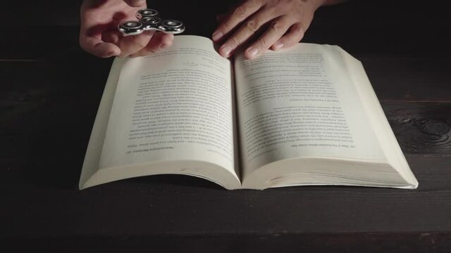 open a book on a wooden table, the spiner is spinning in hand