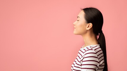 Profile Portrait Of Young Calm Asian Female Standing With Closed Eyes Over Pink Background, Side...