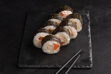 Tasty Japanese food rolls with fish and avocado on black background. Sushi menu.
