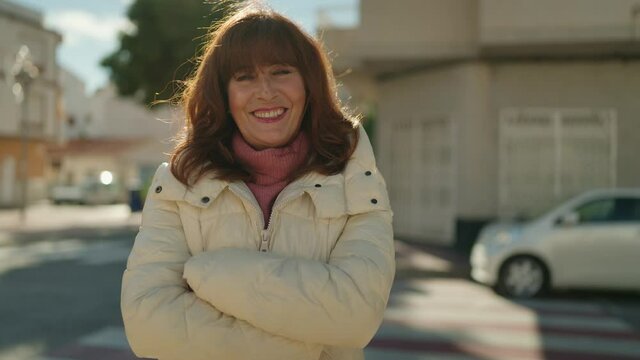Middle age redhead woman smiling confident standing with arms crossed gesture at street