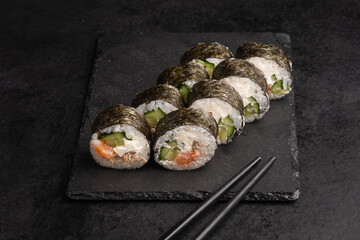 Tasty Japanese food rolls with fish and avocado on black background. Sushi menu.
