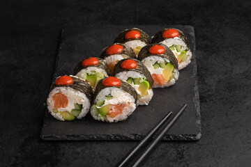 Tasty Japanese food rolls with fish and avocado on black background. Sushi menu.