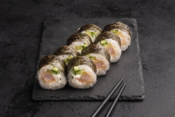 Tasty Japanese food rolls with fish and avocado on black background. Sushi menu.