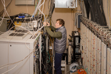 A technician is standing on the stairs and laying wires in the server room. Maintenance of computer...