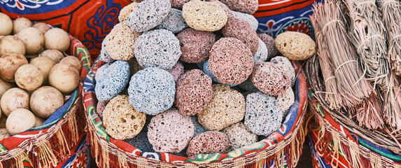 Colored pumice stones for feet in basket as souvenirs for tourists. Volcanic rock with porous...