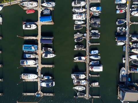 Shooting from the air. Boat pier. There are many boats moored in even rows. Abstraction. Sea trade, travel, fishing, water travel, sports, ecology. There are no people in the photo.