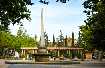Fototapeta na wymiar Fuente del obelisco en el Paseo de San Gregorio con la iglesia de la Virgen de Gracia al fondo, Puertollano, provincia de Ciudad Real, España