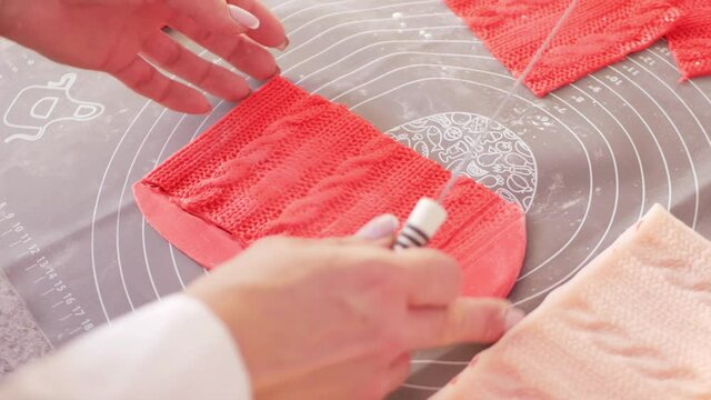 Confectioner Decorates cake with red mastic in form of knitted pattern. Home business, entrepreneur. Cuts