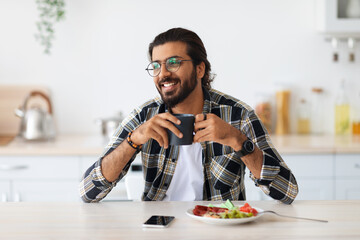 Smiling arab guy having breakfast, looking at copy space