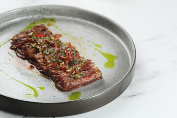 grilled beef chuck steak closeup. sliced steak with chili pepper on ceramic plate