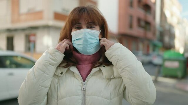 Middle age redhead woman smiling confident wearing medical mask at street