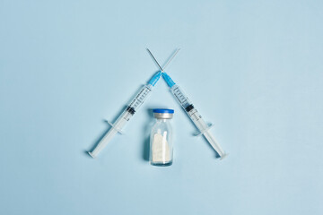 Anti vaccination or vaccine skepticism concept. Syringes crossed on bright blue background....
