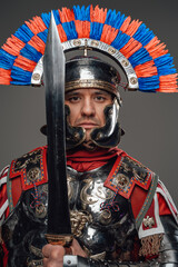 Proud roman soldier with gladius posing against gray background